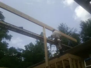 Carpenter setting a ridge beam over a new addition frame — Ice Dam Removal by Roofing Brothers in Barataria