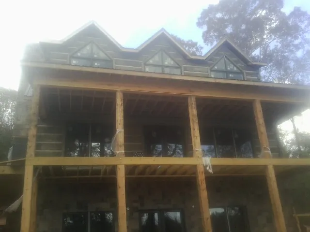 Dormers and porch framing on a large log home under construction — Roof Coating work by our crew in Barataria