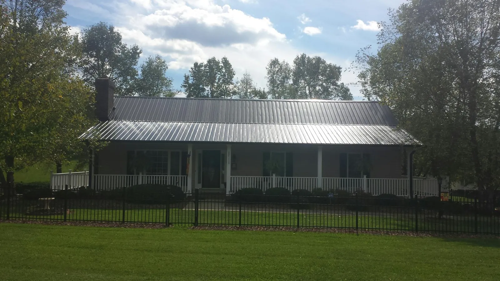 Gray metal roof on a brick ranch with a full width front porch — Gutter Guard Installation work by our crew in Barataria