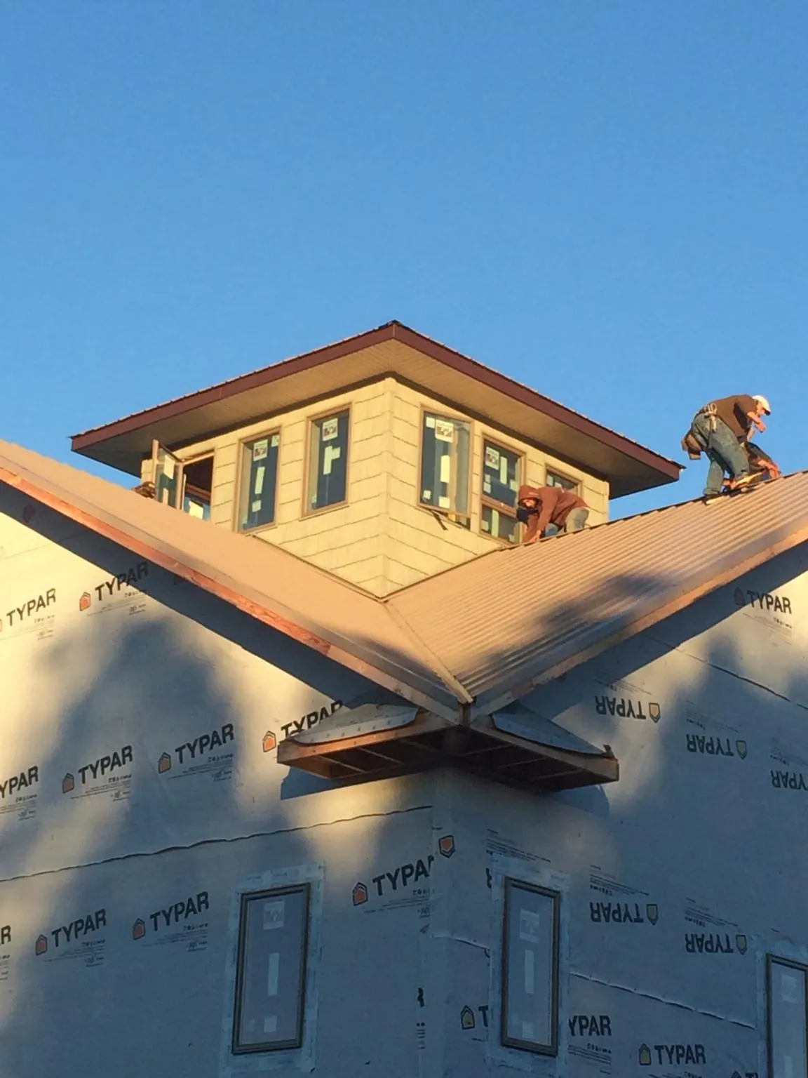 Roofers working around a rooftop cupola on a new metal roof at sunset — Roof Waterproofing in Barataria by Roofing Brothers